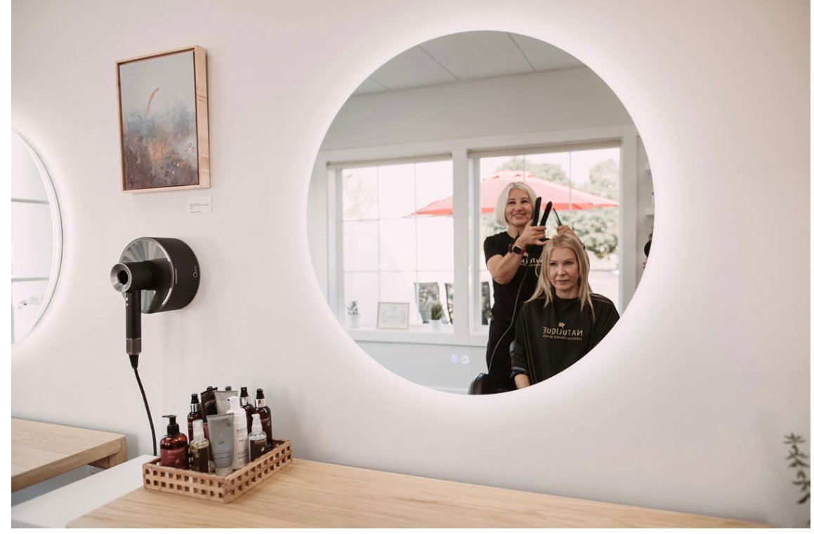 Hairstylist Lone Holt curling a client's hair at DaneStyles Hair Artistry organic salon in Snohomish, WA with Natulique products and modern styling station